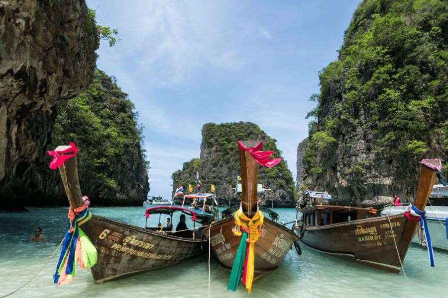 Barcos tradicionais de cauda longa navegando nas águas turquesa de Koh Phi Phi, Tailândia