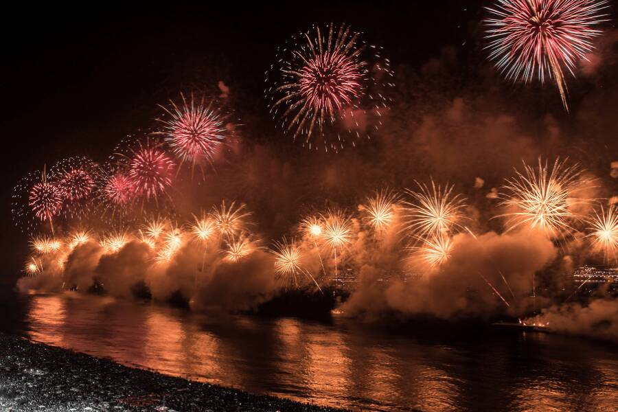 Fogo de artifício espetacular a iluminar a praia e o mar durante a celebração do Réveillon.